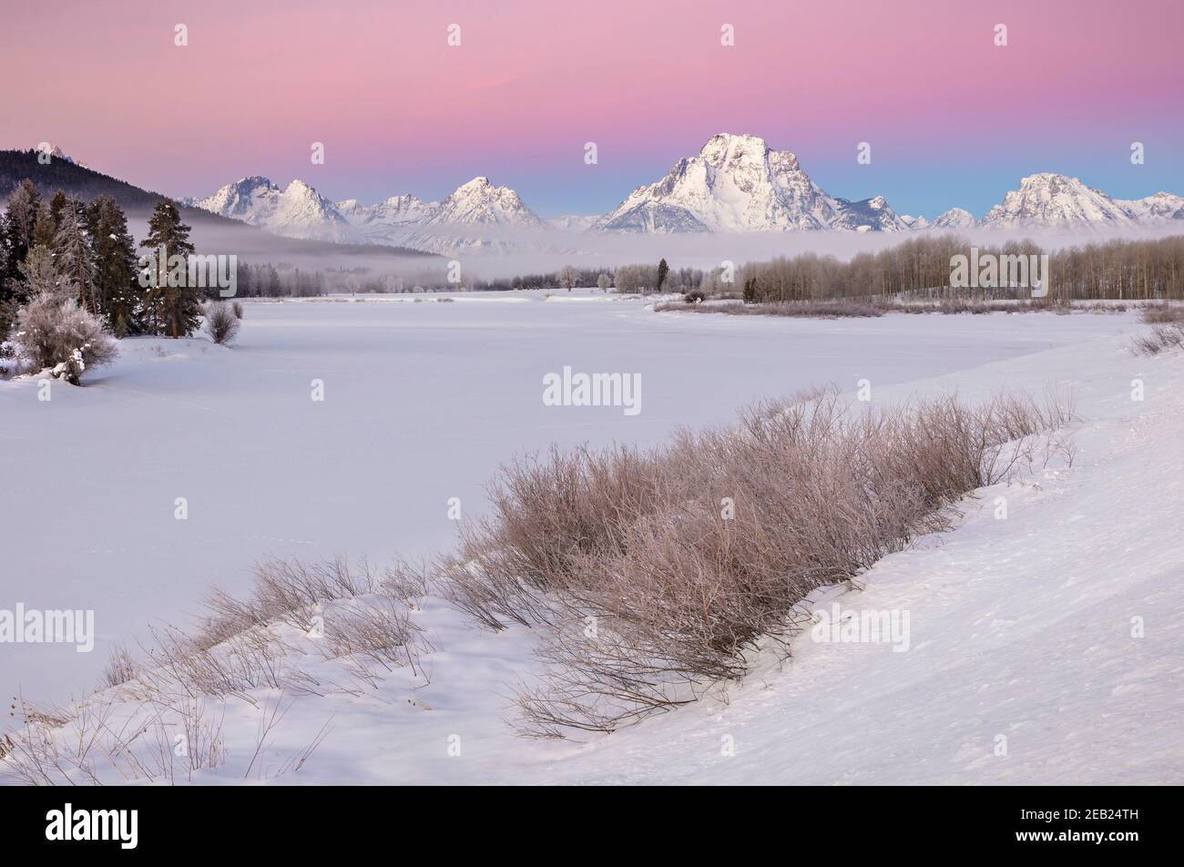 Grand Teton National Park, WY:  Mount Moran and Teton Range at dawn with low lying fog from the Oxbow of the Snake River in winter Stock Photo