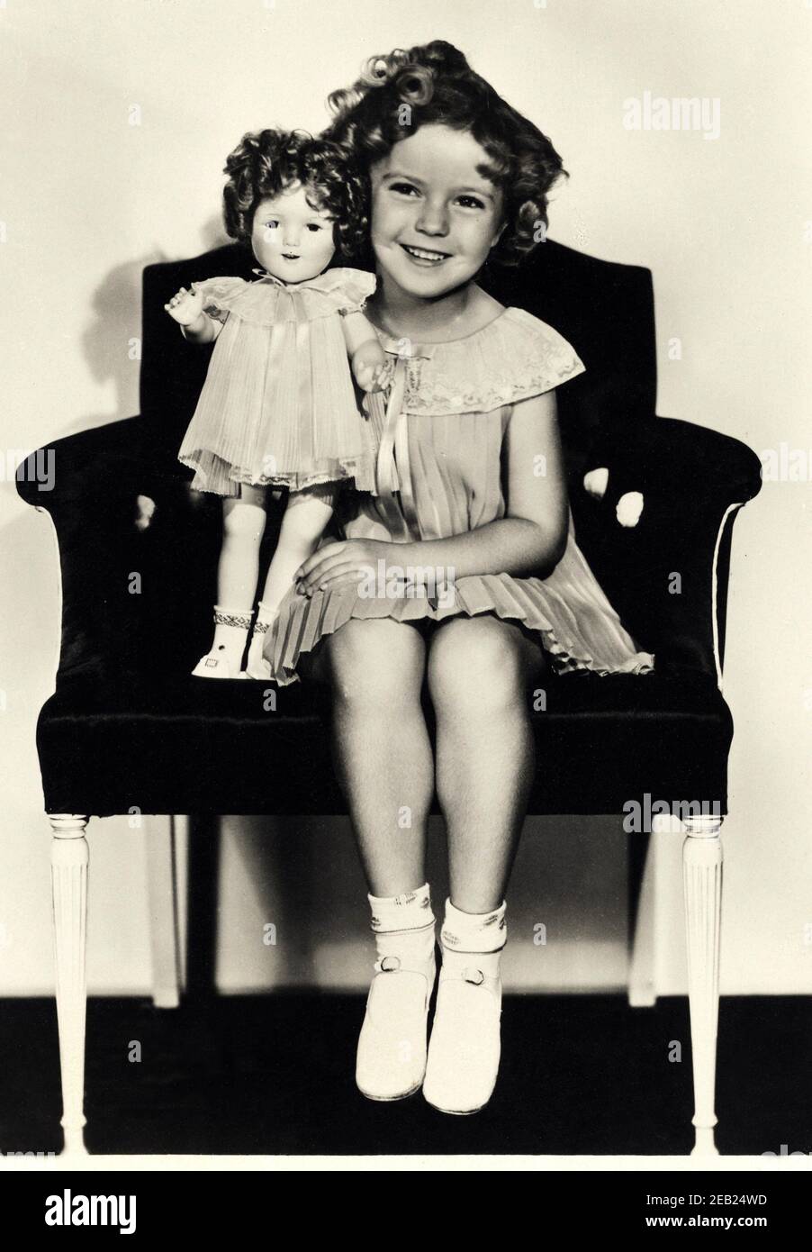 1935  ca. , USA  : The child actress SHIRLEY TEMPLE ( 1928 -  2014 ) with a look-a-like doll of himself , Fox movie pubblicity still   - MOVIE - FILM - CINEMA - portrait - ritratto  - boccoli - riccioli - curls   - bambino prodigio  -  bambola - bambole - giocattolo  - giocattoli -  celebrity celebrities actors actor actress personality personalities with dolls  - toy - toys  - celebrità attori attrici personalità con - smile - sorriso  - scarpe alla bebè - shoes - poltrona - pizzo - lace - collar - colletto  ----  Archivio GBB Stock Photo