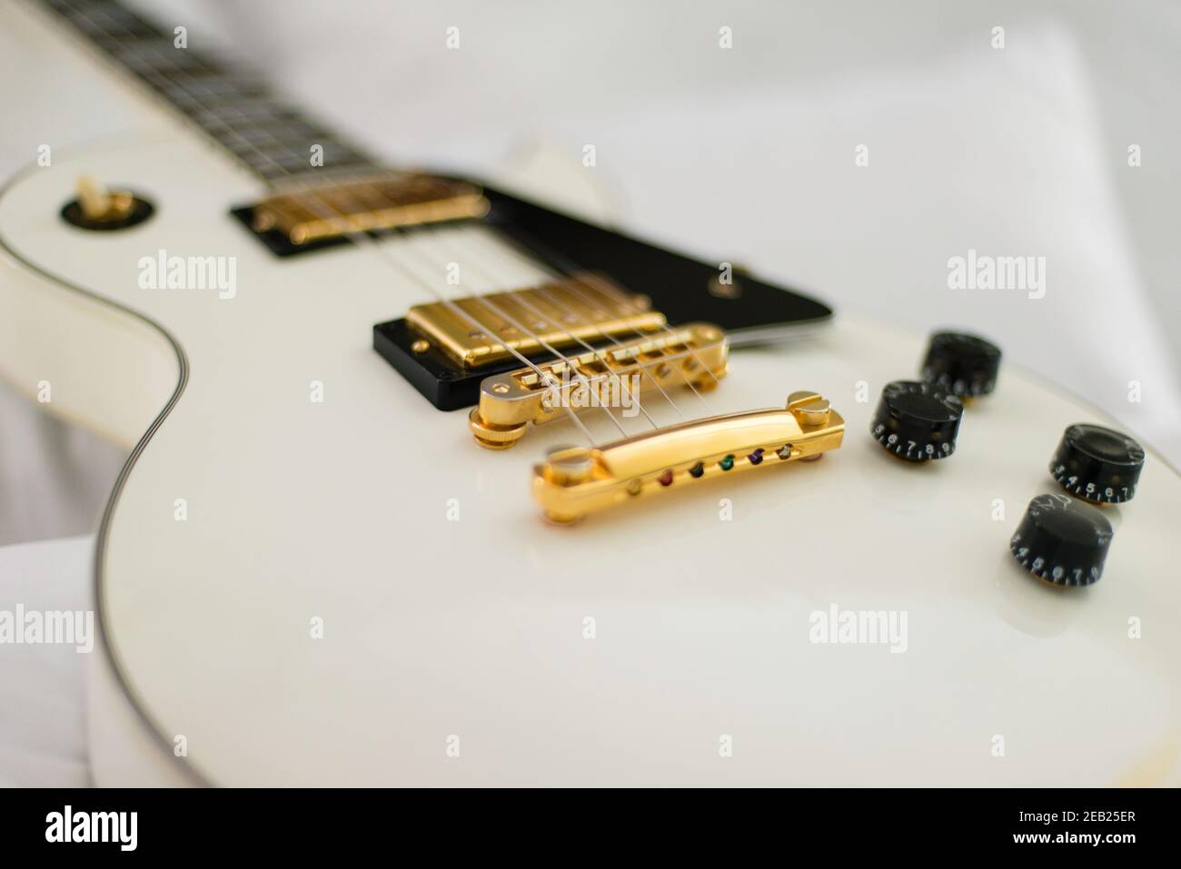 White Gibson guitar on background of white bed sheets. Stock Photo