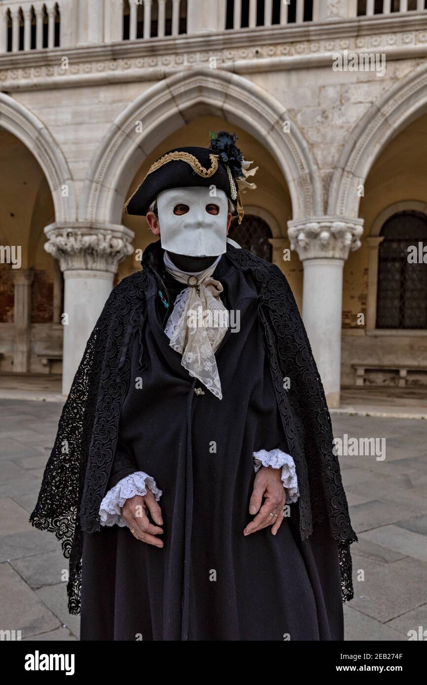 Traditional Bauta costume with cape, feathered tricornered hat and white lava mask. Venice Carnival time February 2021. Stock Photo