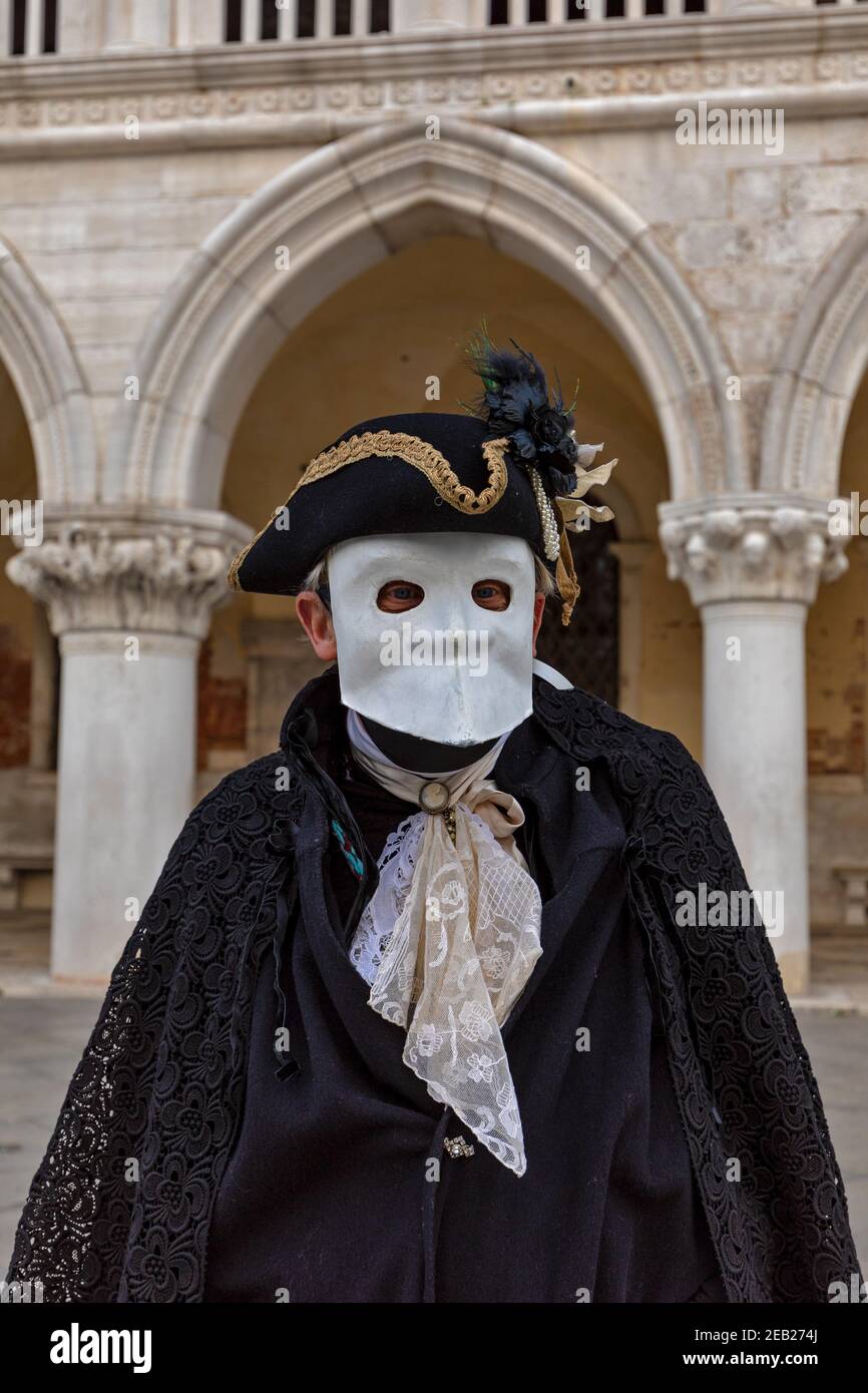 Traditional Bauta costume with cape, feathered tricornered hat and white lava mask. Venice Carnival time February 2021. Stock Photo