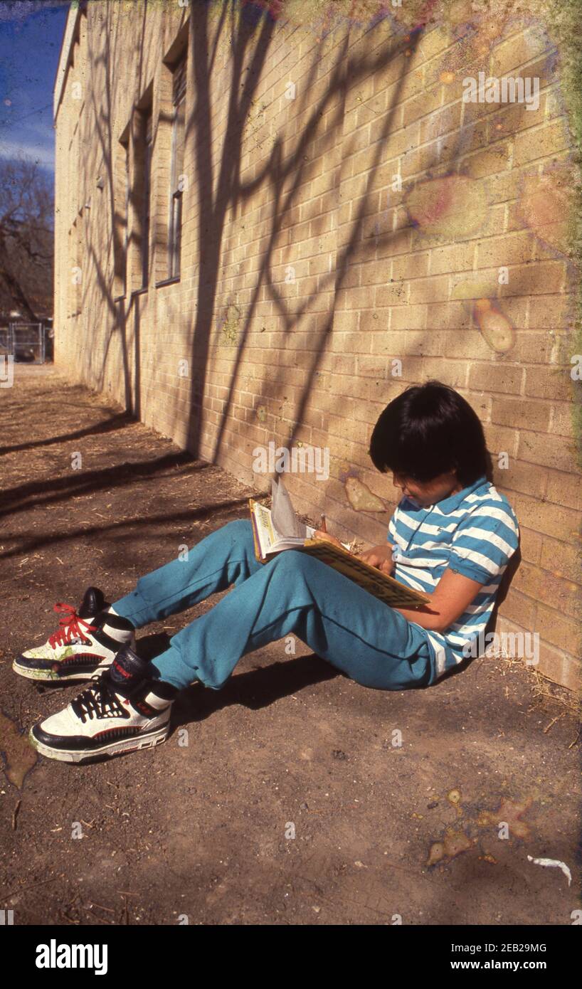 Austin, Texas USA: Hispanic third grade boy doing homework lesson on school playground at Walnut Creek Elementary. ©Bob Daemmrich    BAD8672C Stock Photo