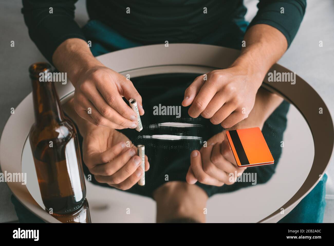Alcohol and drug addiction. Junkie man with two cocaine lines on mirror, rolled banknote and bottle of beer. Detrimental lifestyle. Bad habits Stock Photo
