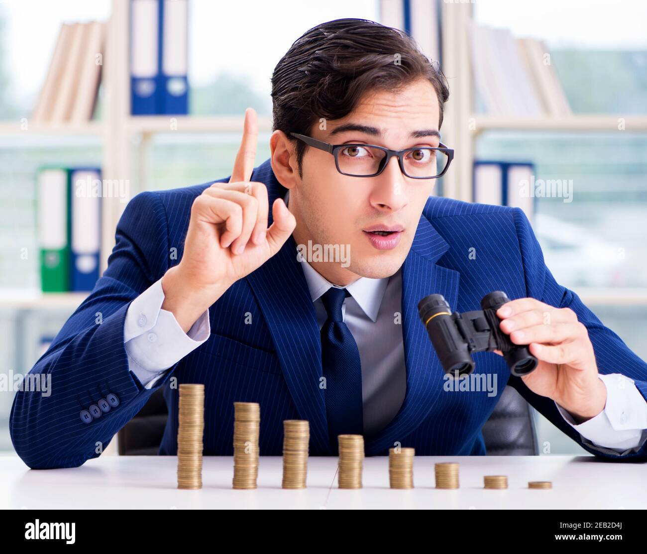 The businessman with stacks of coins in the office Stock Photo - Alamy