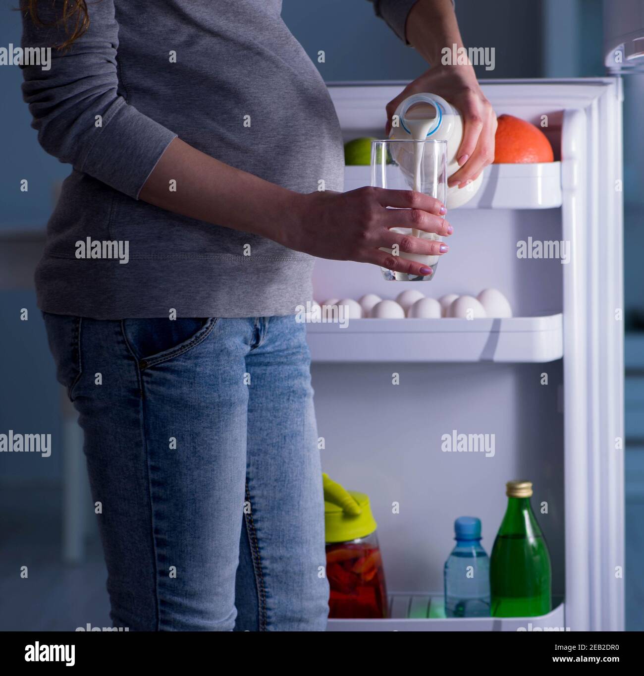 The pregnant woman near fridge looking for food and snacks at night Stock Photo