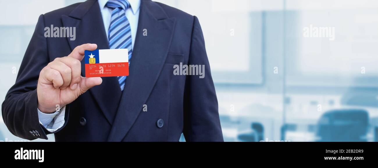 Cropped image of businessman holding plastic credit card with printed flag of Chile. Background blurred. Stock Photo