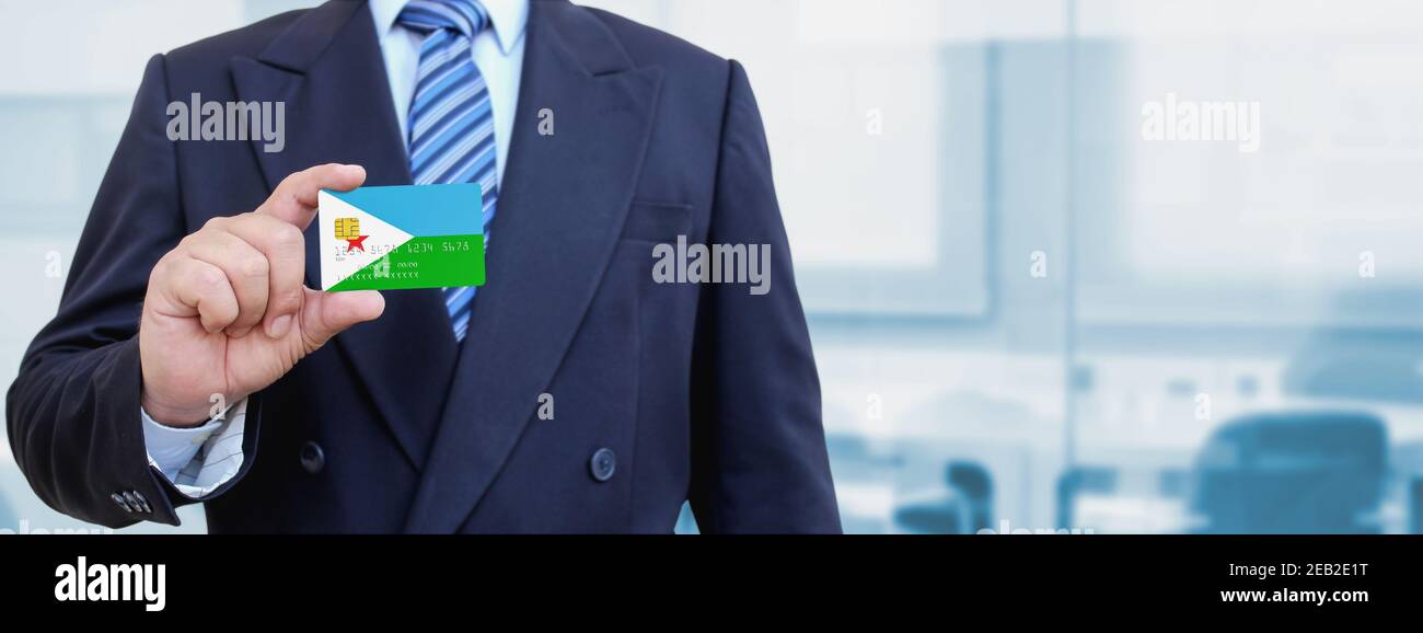 Cropped image of businessman holding plastic credit card with printed flag of Djibouti. Background blurred. Stock Photo