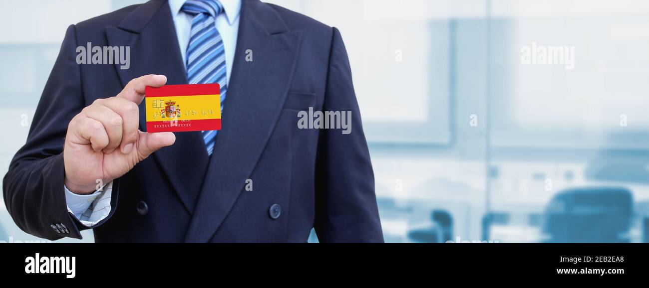 Cropped image of businessman holding plastic credit card with printed flag of Spain. Background blurred. Stock Photo