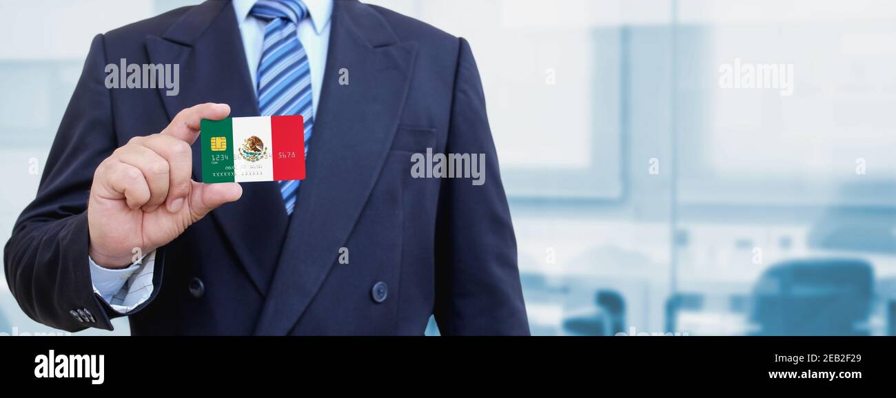 Cropped image of businessman holding plastic credit card with printed flag of Mexico. Background blurred. Stock Photo