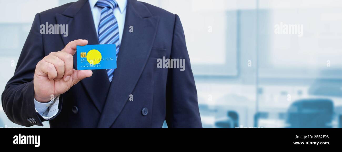 Cropped image of businessman holding plastic credit card with printed flag of Palau. Background blurred. Stock Photo
