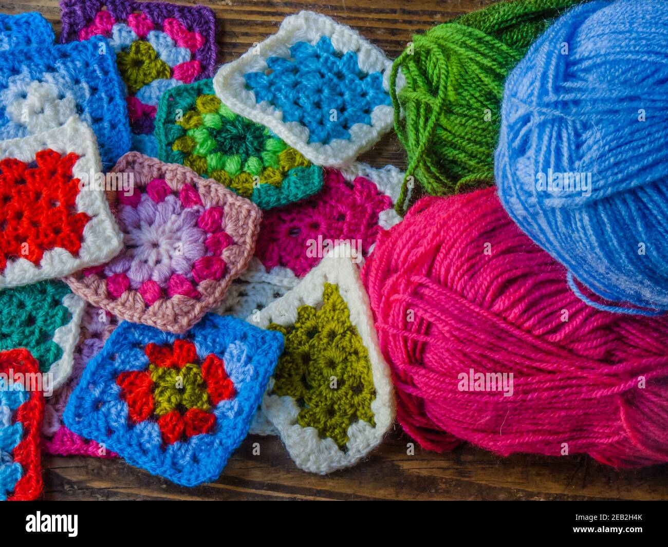 Skeins of colored wool and granny square on a wooden board Stock Photo