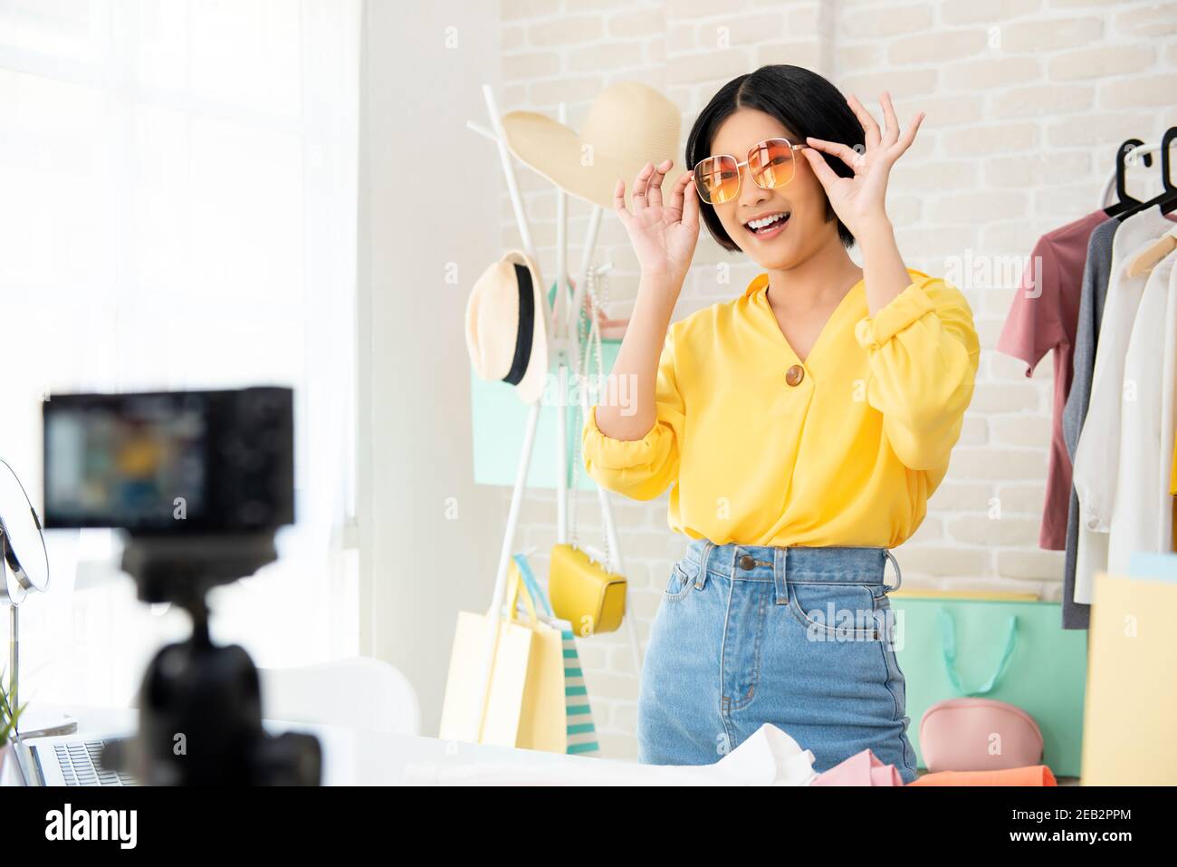 Young Asian woman fashion vlogger trying on clothes and accessories live streaming online Stock Photo