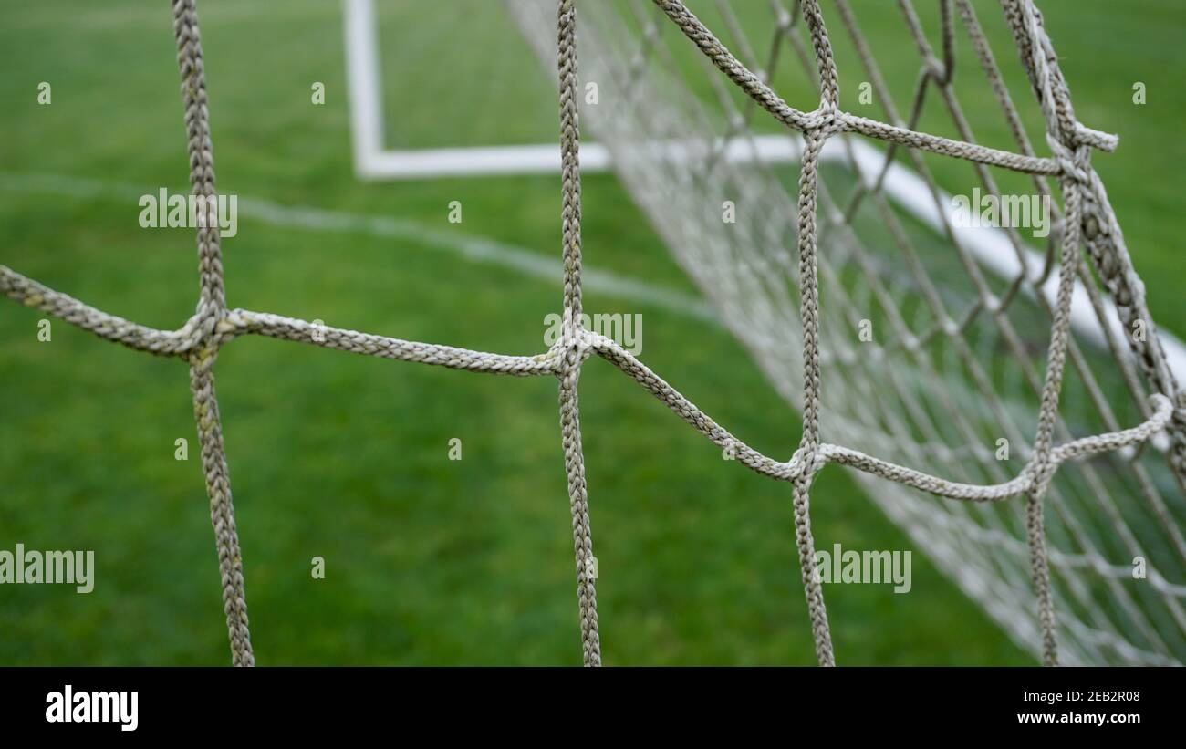 Outdoor white soccer goal frame and twine mesh game netting. Empty goalie box. Green grass and net pattern. Stock Photo