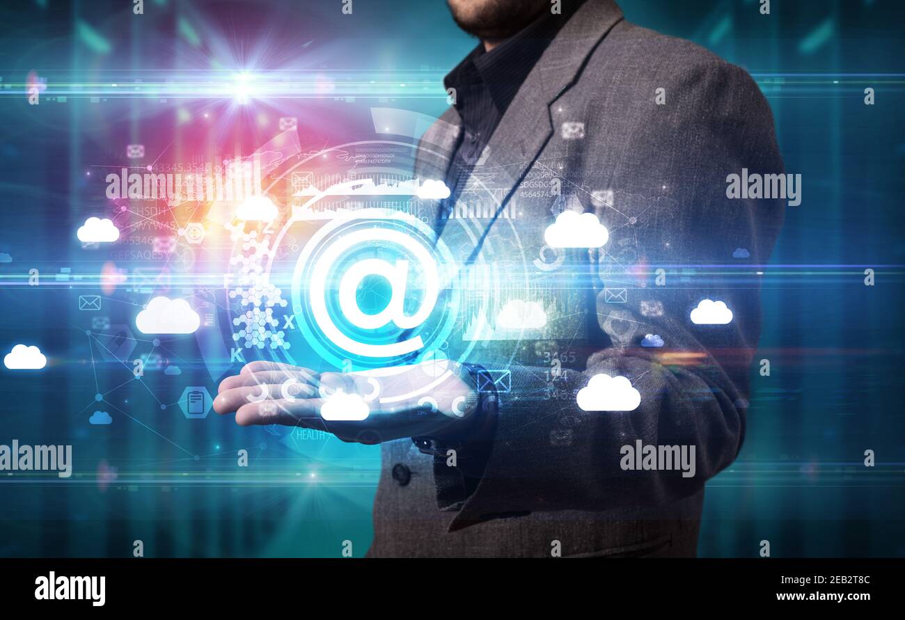 Businessman holding @ icon in his hands with multiple technology ...