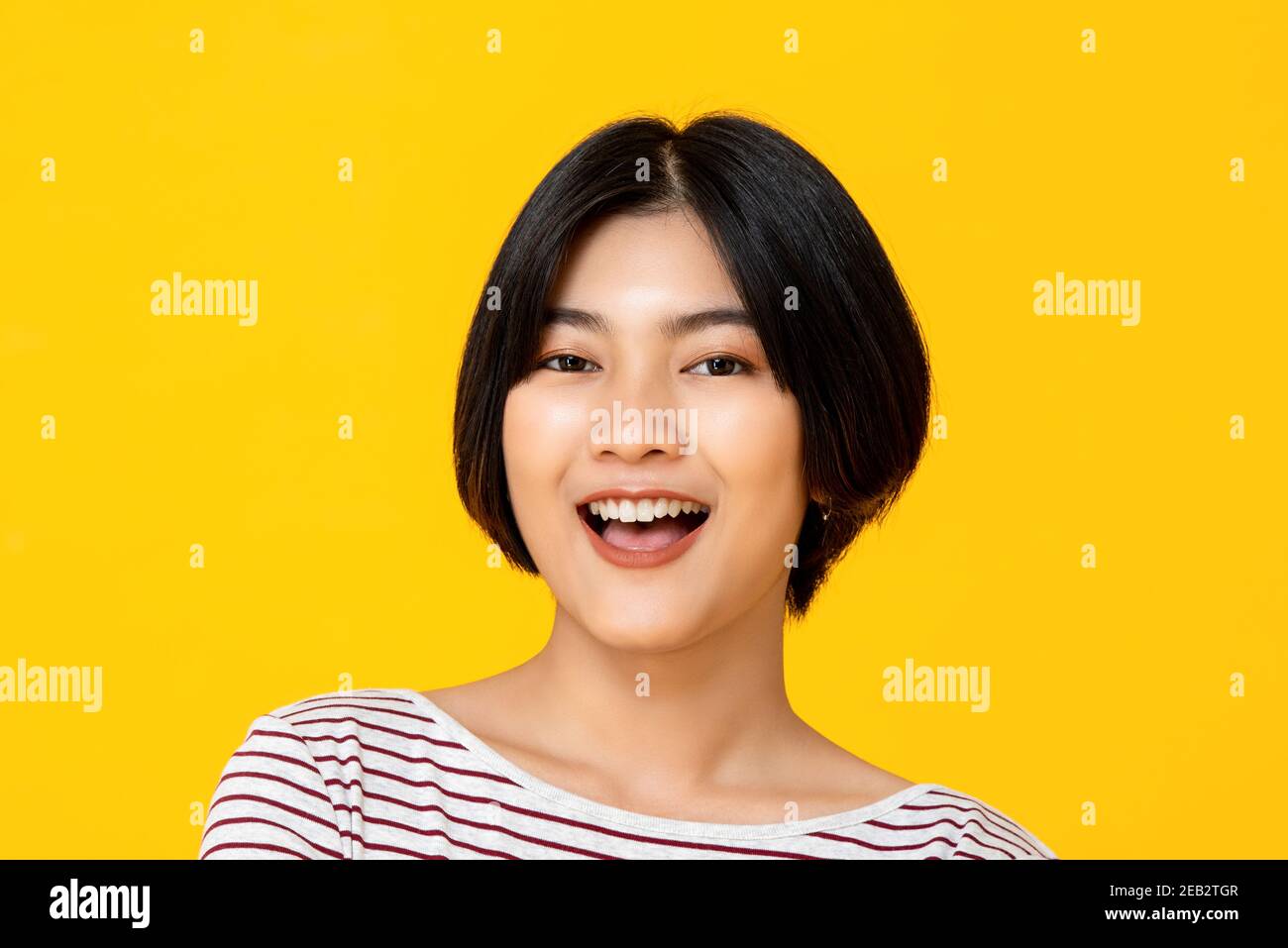 Young beautiful smiling Asian woman isolated in colorful yellow studio background Stock Photo
