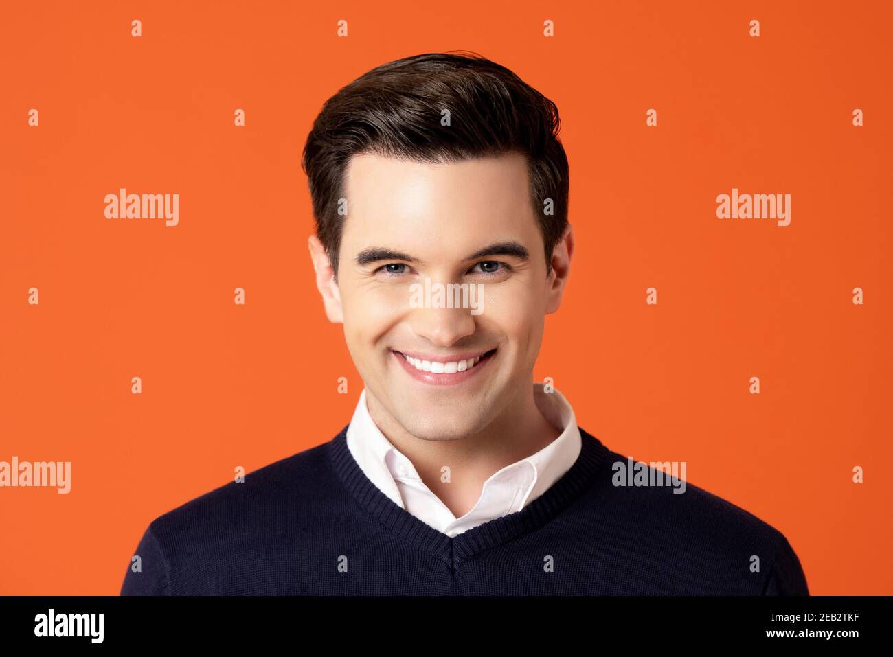 Handsome friendly smiling caucasian man on colorful orange studio background Stock Photo