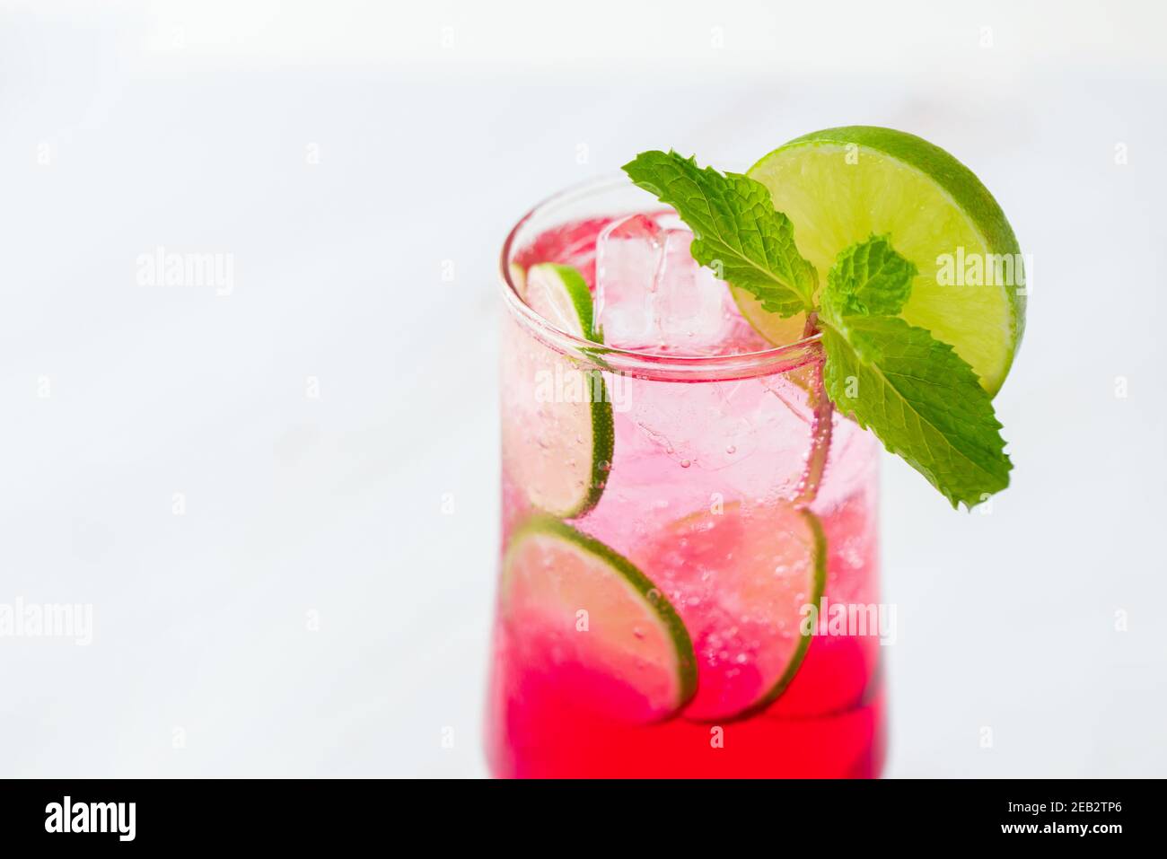 Refreshing strawberry lemonade soda mocktail drink in the glass garnished with sliced lime and peppermint Stock Photo