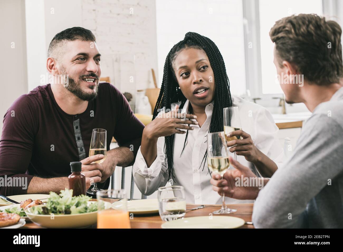 Group of diverse neighbors having conversation in social gathering party while drinking a glass of white wine Stock Photo