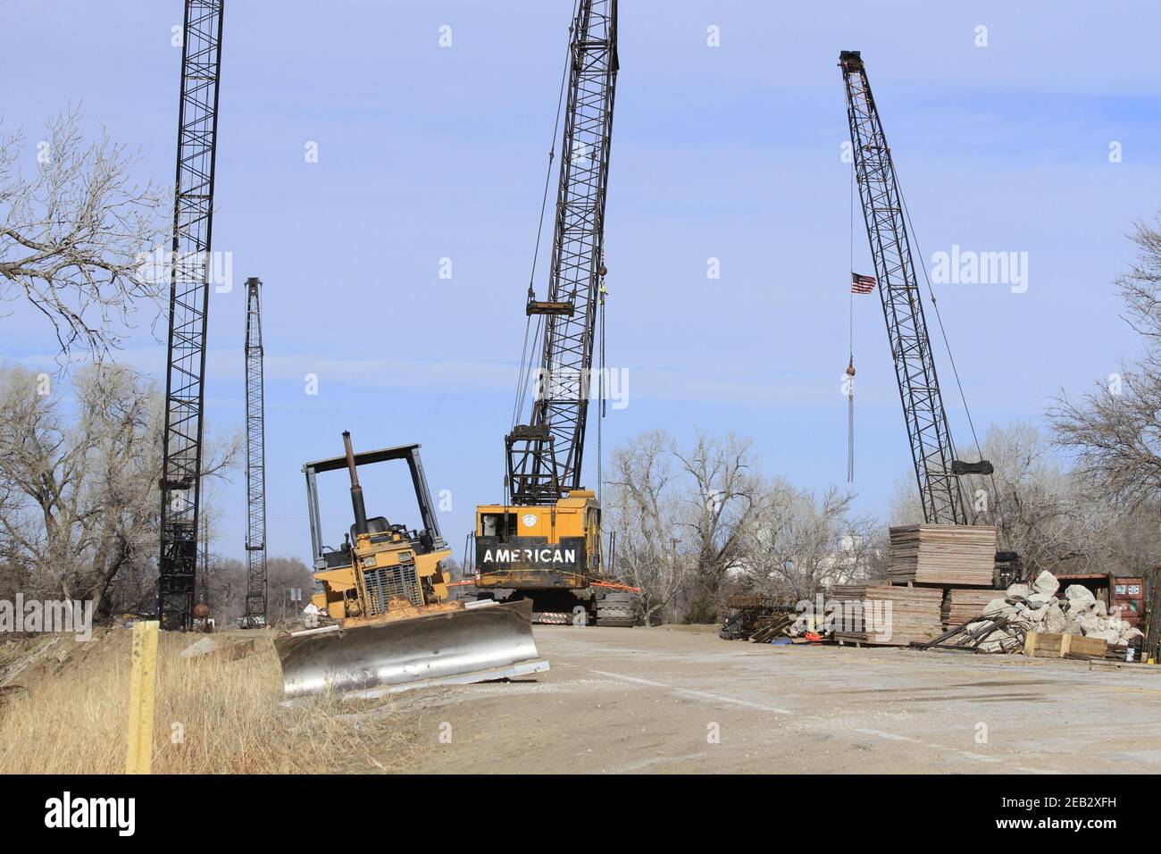 River Bridge repair with Cranes and a Bulldozer with blue sky and tree's south of Nickerson Kansas USA out in the country on a winter day. Stock Photo