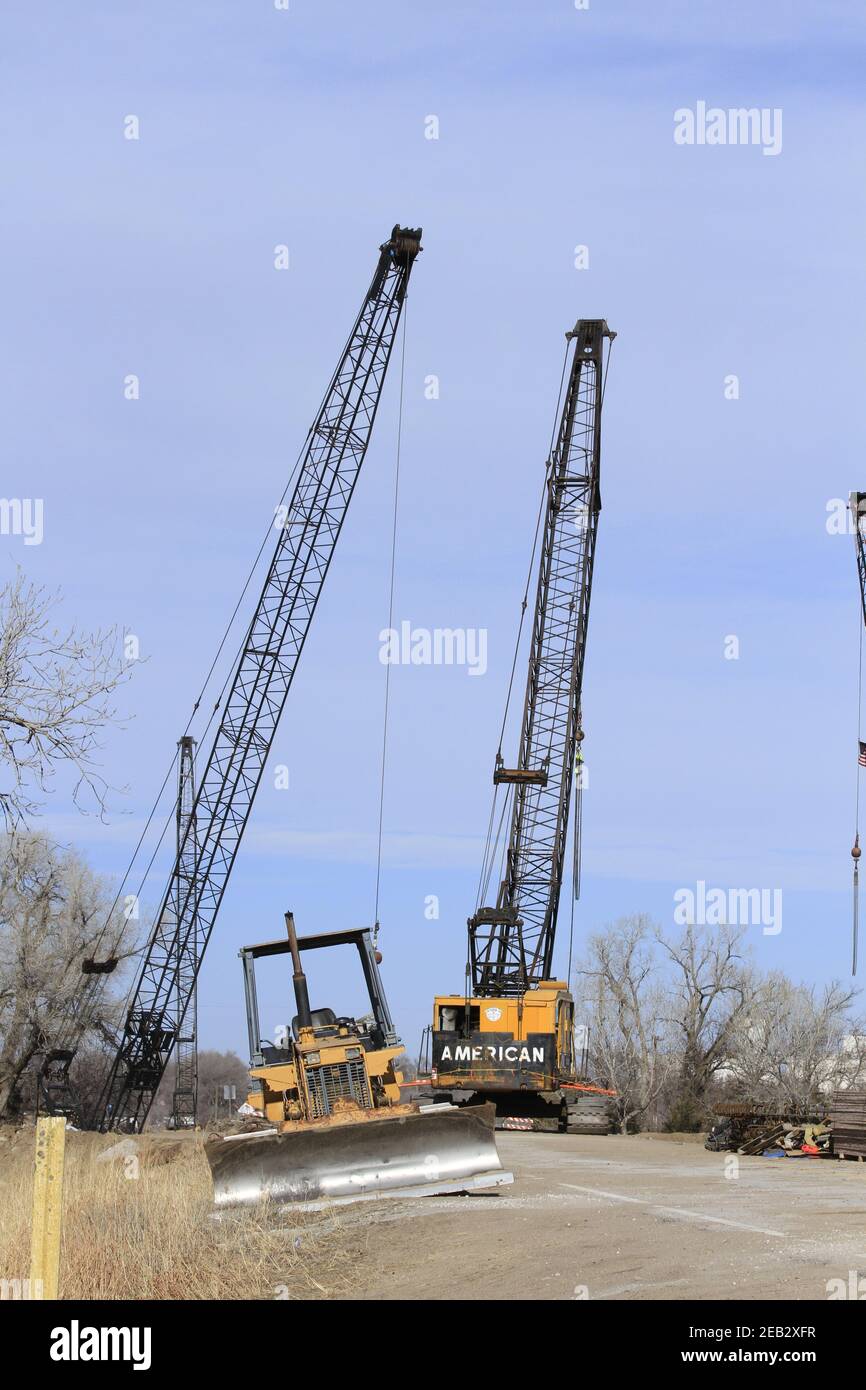 River Bridge repair with Cranes and a Bulldozer with blue sky and tree's south of Nickerson Kansas USA out in the country on a winter day. Stock Photo