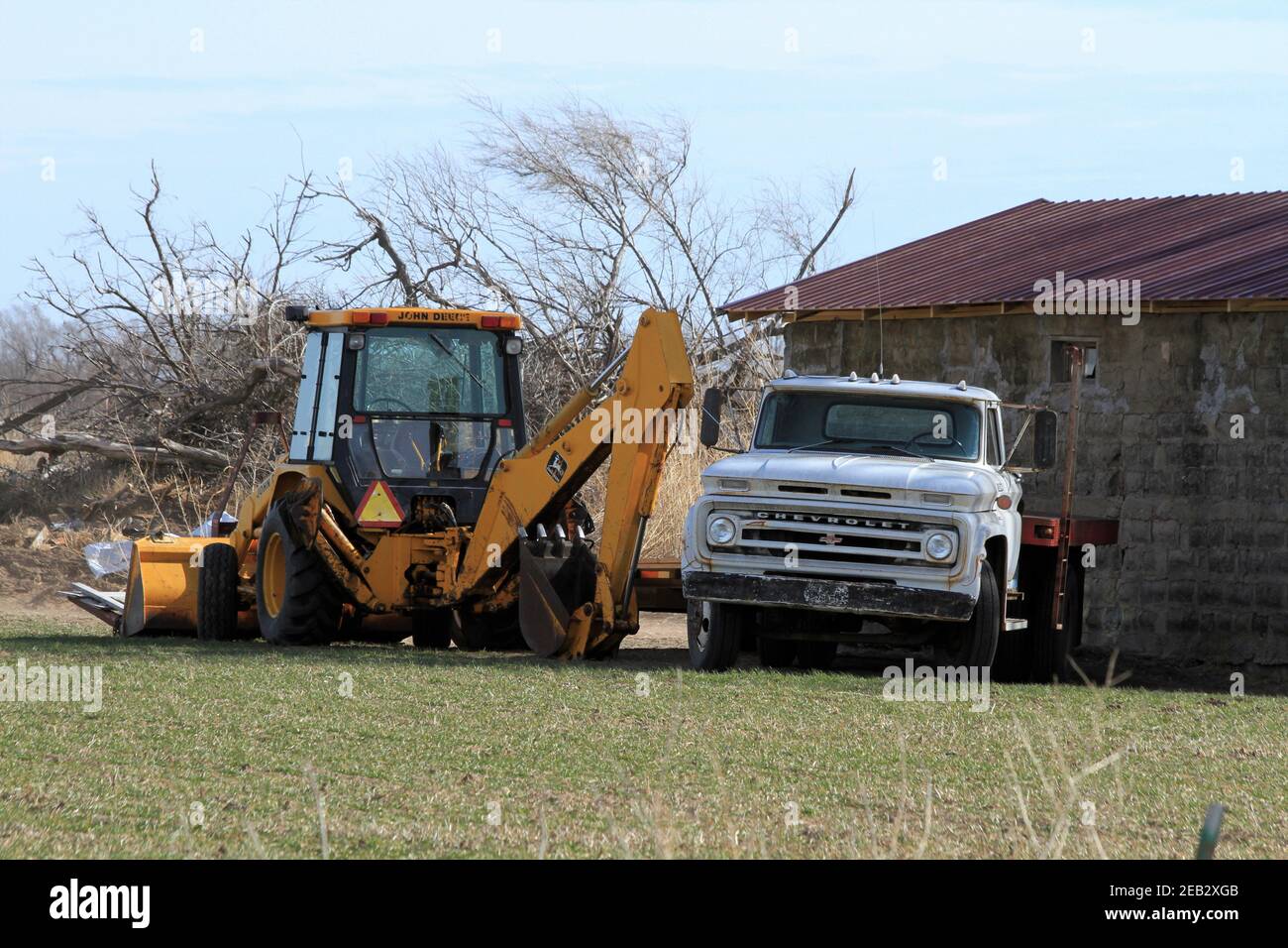 John Deere Tractor with a backhoe, front end loader, and a Chevrolet flat bed Truck ready for work out ion the country. Stock Photo