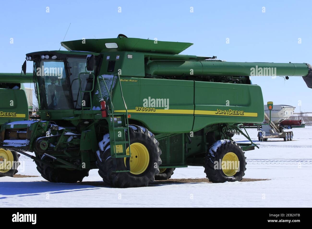 John Deere combine in the winter time at a Dealership that's in Greensburg Kansas USA with snow and blue sky. Stock Photo