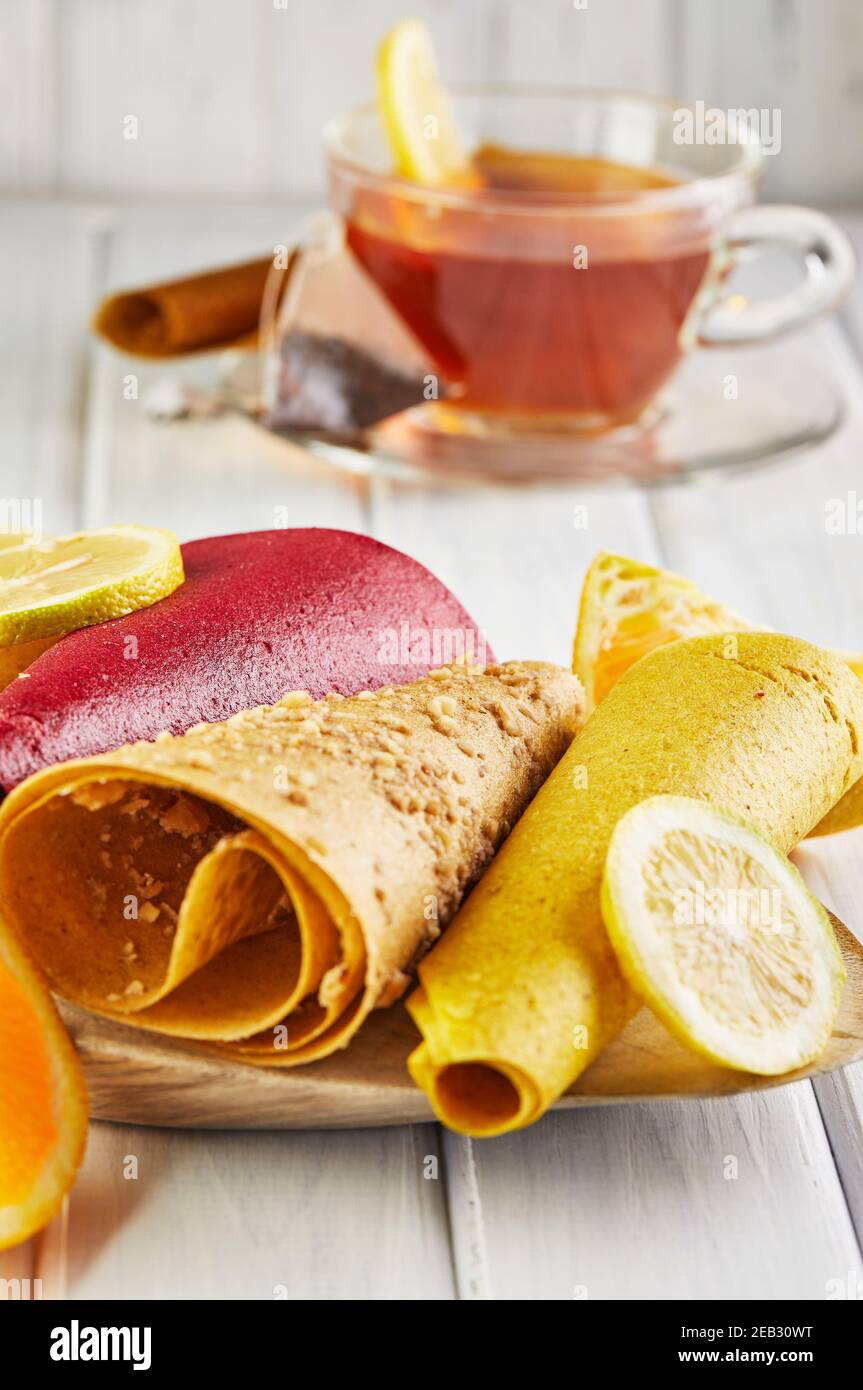 Sweet pastille of pure fruits in rolls with citrus fruits and tea with lemon. Healthy sweets - lollipops, fruit chips. Natural sweets from berries and Stock Photo