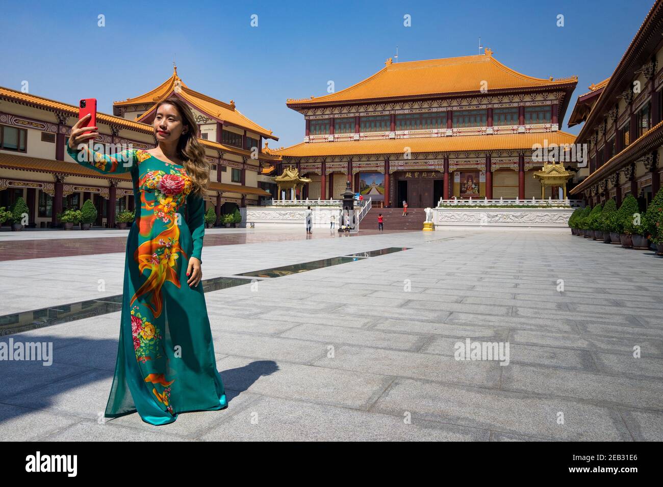 Vietnamese girl in traditional ao dai taking a selfie during Chinese new year at Fo Guang Shan temple in Bangkok Stock Photo
