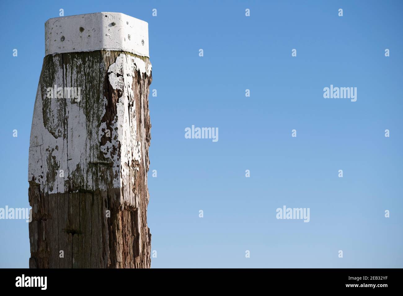 Mooring post or pole against a blue sky. Space for text on the right Stock Photo