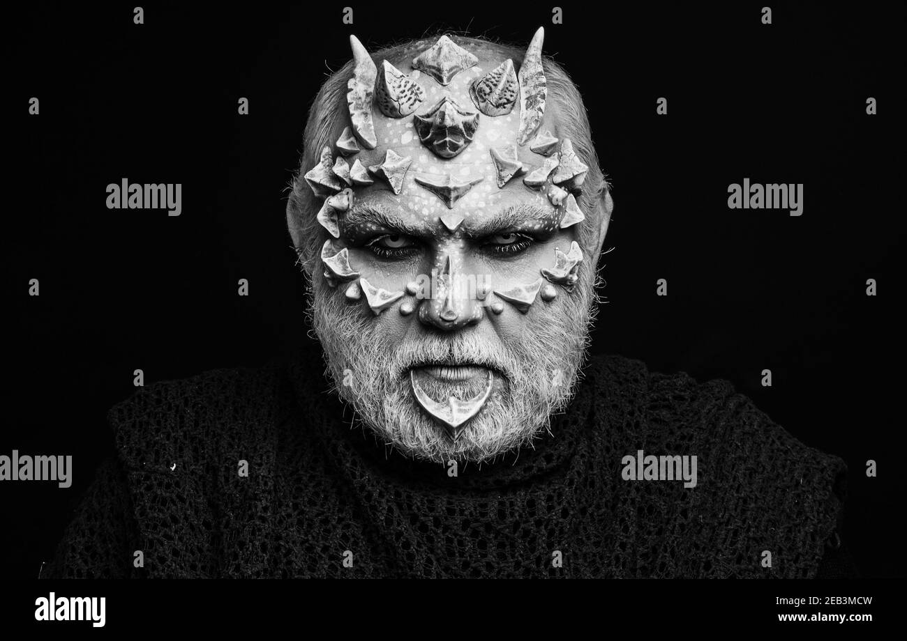 Devil isolated on black. Alien or reptilian makeup with sharp thorns and warts. Horror and fantasy concept. Man with dragon skin and beard. Monster. Stock Photo