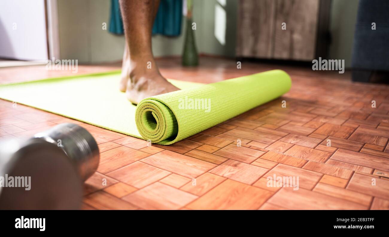 Young man at home arranging yoga mat before starting exercise - Concept of medical, helathcare, Fitness. Stock Photo
