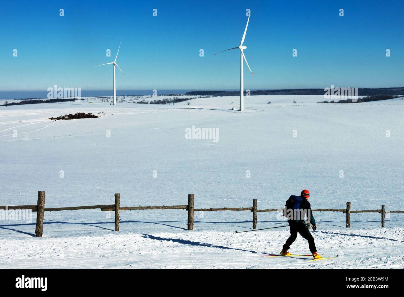 Plateau scenery, snow-covered mountain meadows, wind turbines Ore Mountains Czech Republic landscape single skier cross country skiing Stock Photo