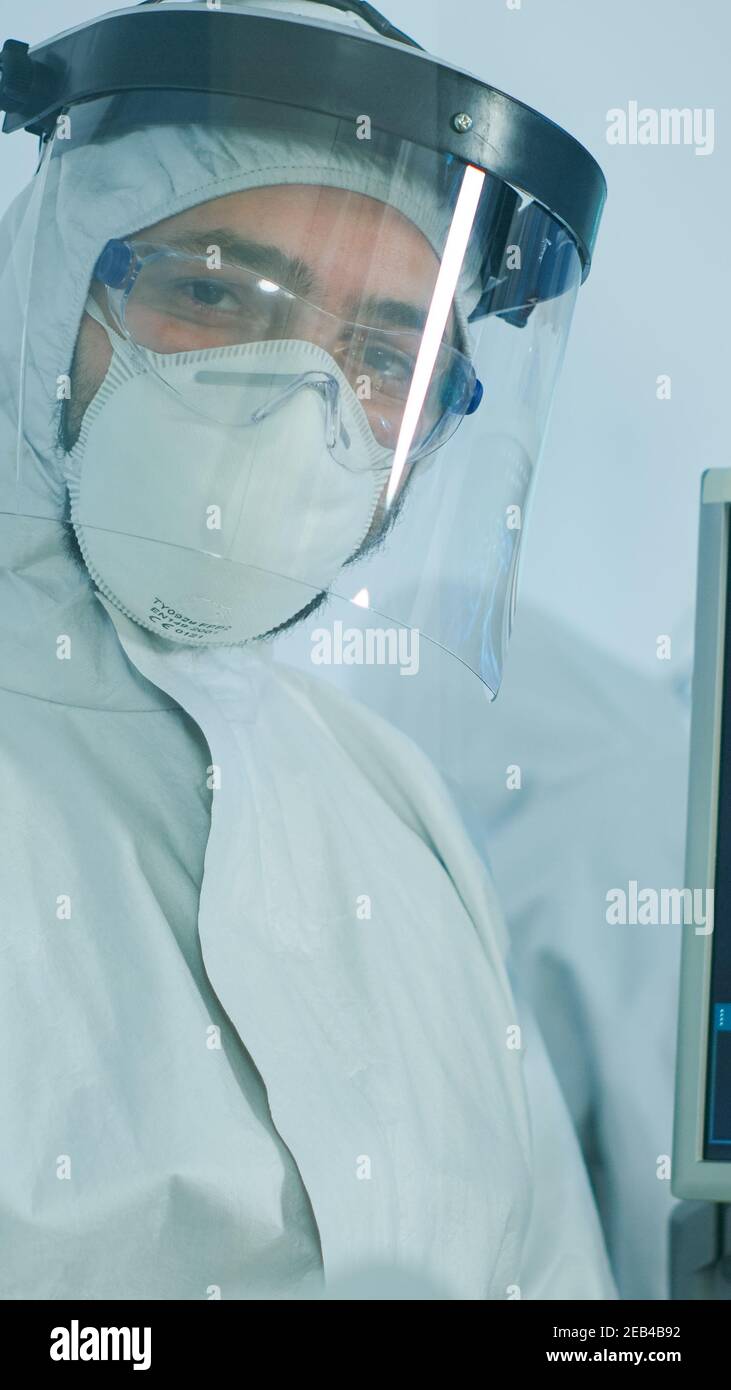 Microbiologist in ppe suit standing in laboratory looking at camera ...