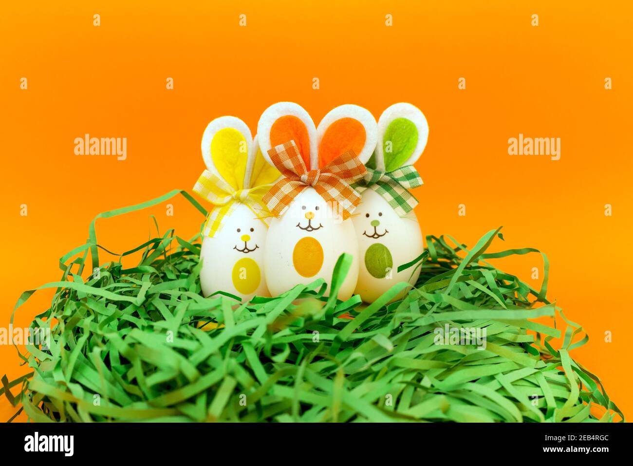 Three Easter eggs with bunny ears on nest spring yellow background ...