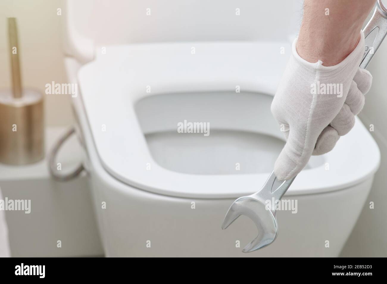Hand hold wrench tool on toilet seat background Stock Photo