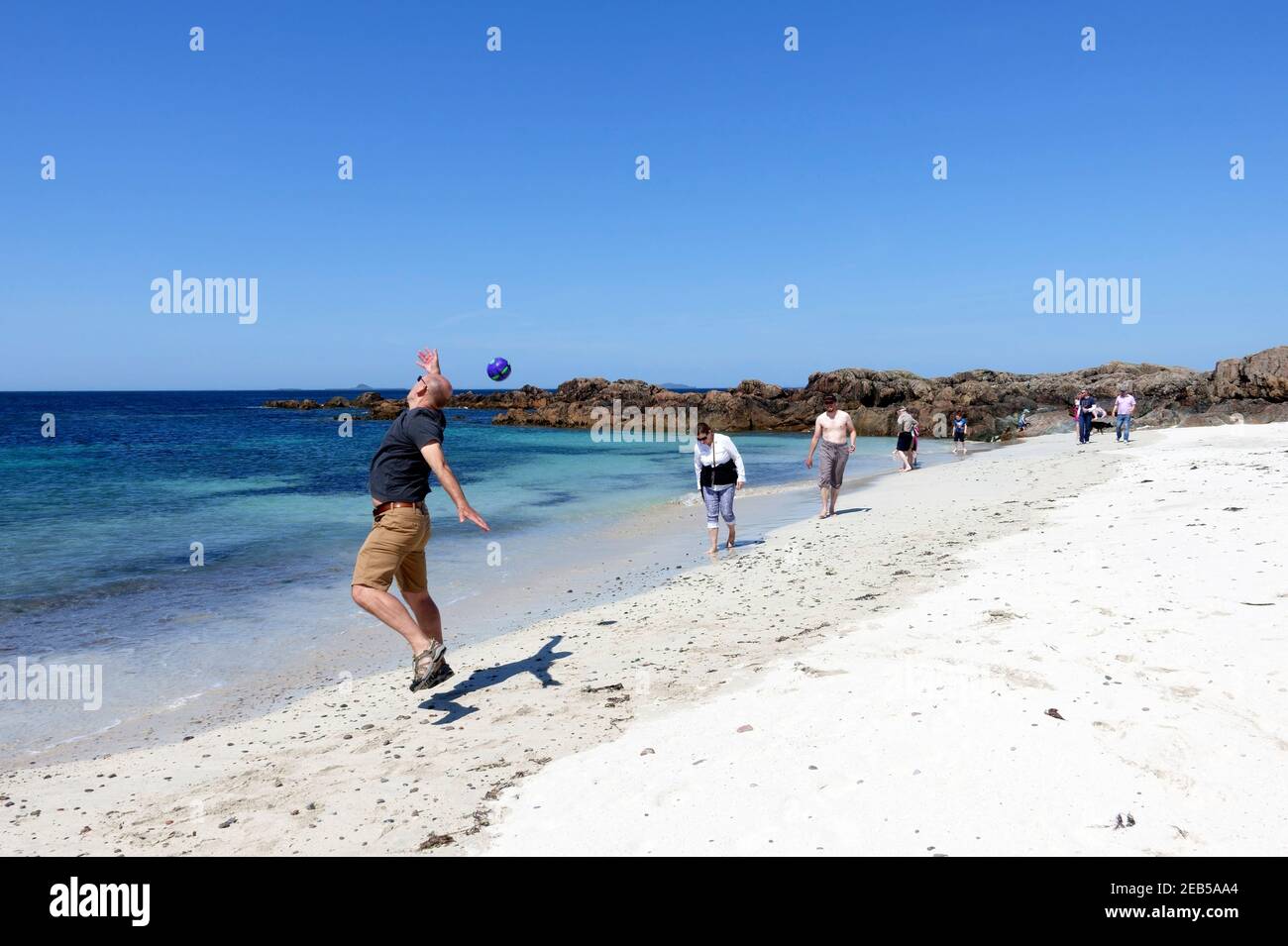 Man trying to catch a ball on the north west beach on Iona Stock Photo