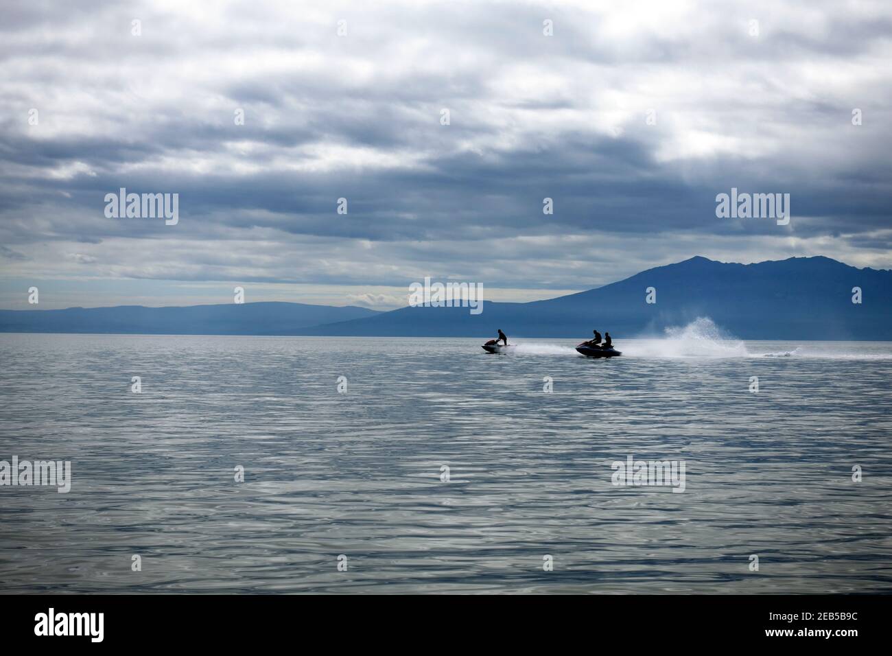 Jet ski riders on the Firth of Clyde with the hills of the Isle of Arran in the background, Scotland Stock Photo