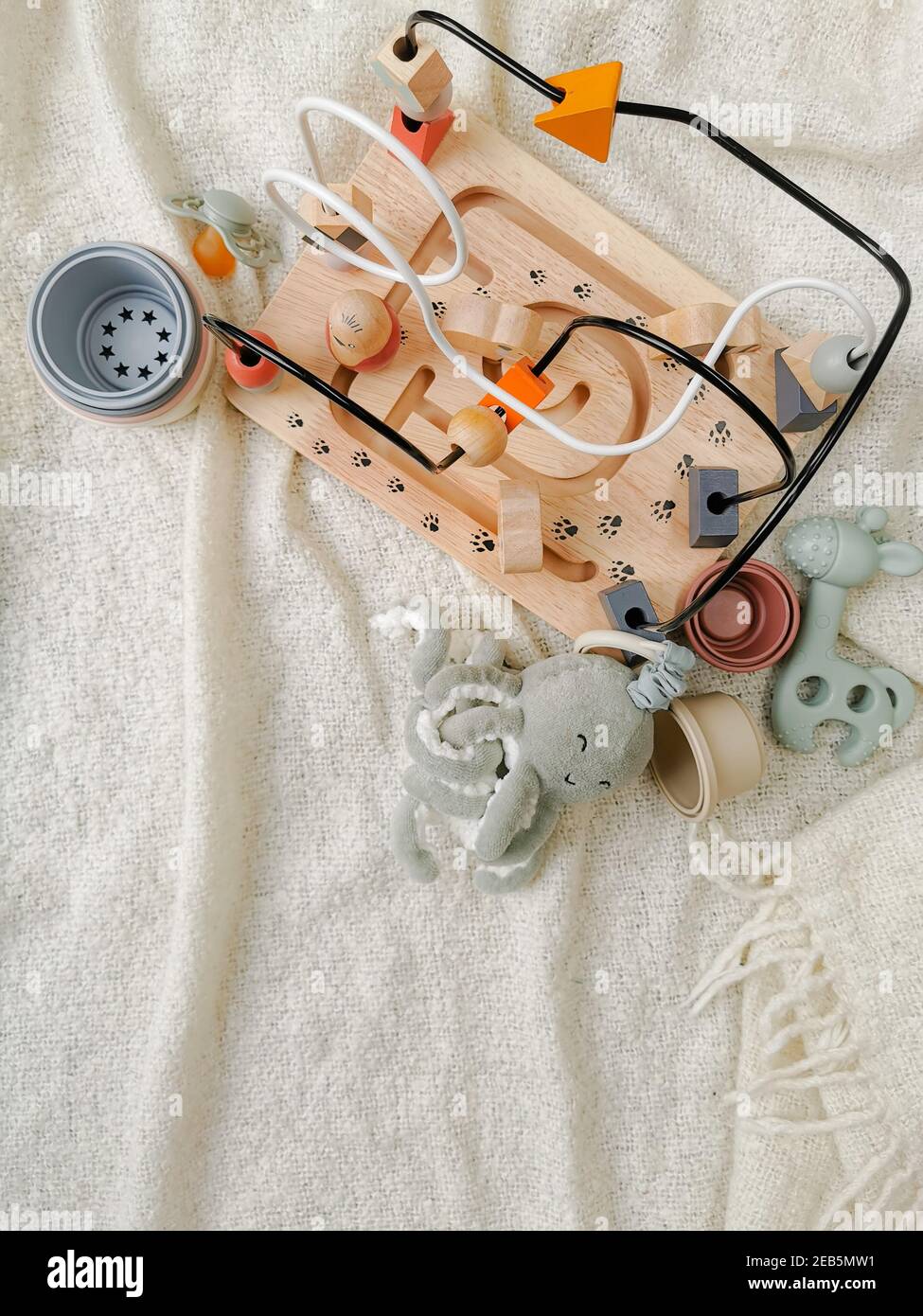 Gender neutral toys for babies in muted soft colors. Wooden blocks en bead frame, teething toy. Flat lay. Gender neutral parenting. Stock Photo