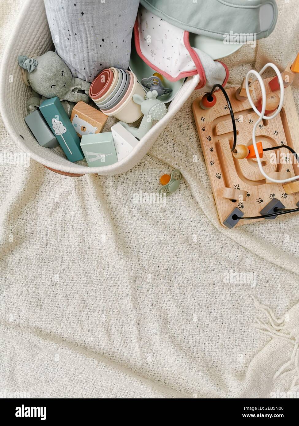 Gender-neutral toys for babies in soft colors. Wooden blocks, beads toy, pacifier, ... Gender neutral parenting. Flat lay. Stock Photo