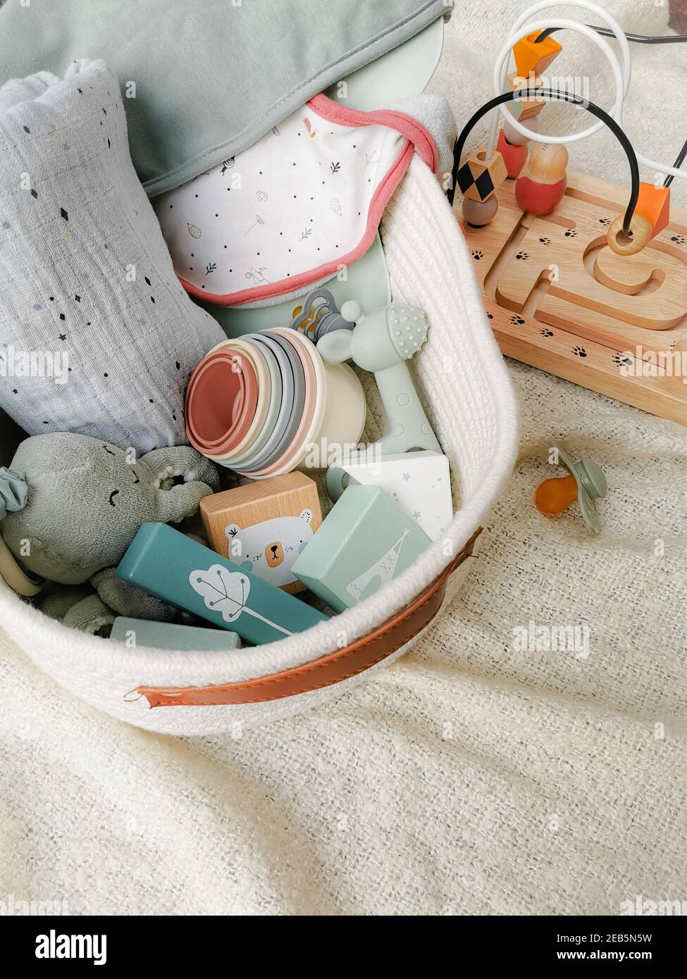 Gift set for a baby shower with toys in soft gender-neutral colors such as blocks, teething toy, ... . Gender neutral parenting concept. Stock Photo