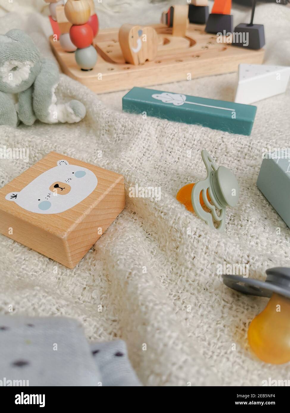 Gender neutral toys for babies in muted soft colors such as wooden blocks and pacifiers. Gender neutral parenting. Stock Photo