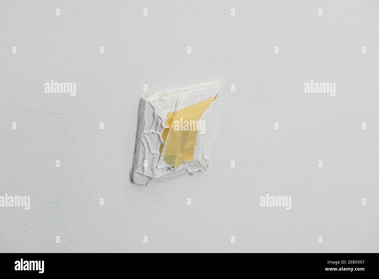 Power socket covered with masking tape while the white wall being
