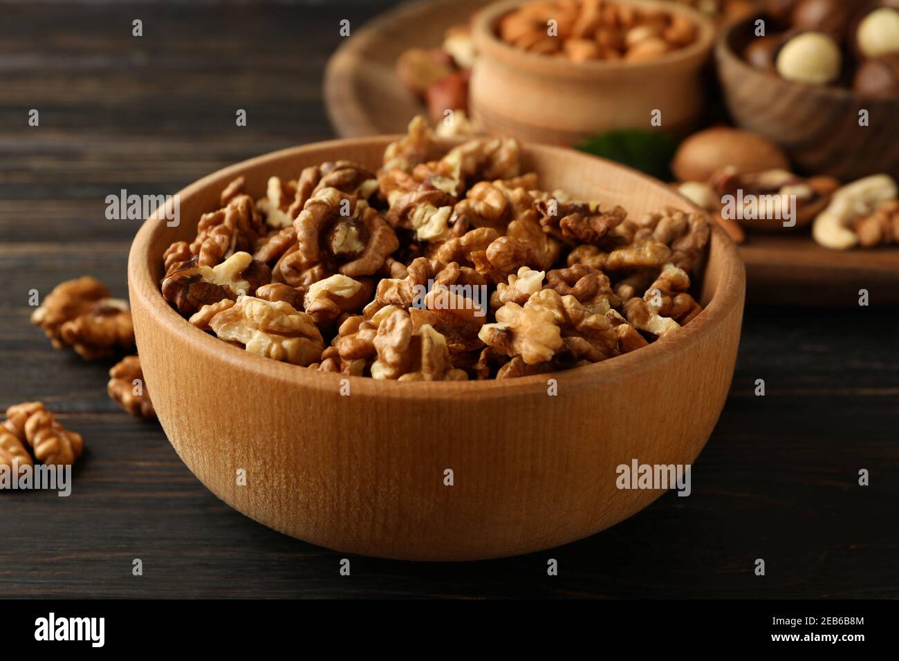 Wooden bowl with walnuts on wood background, close up Stock Photo