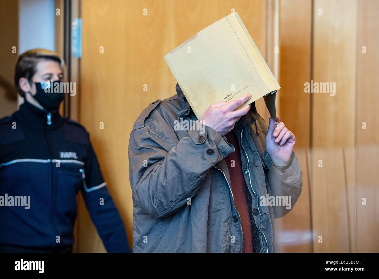 North Rhine-Westphalia, Münster, 12 February 2021: The 50-year-old defendant from Hanover enters a room at Münster Regional Court with a file in front of his face in the Münster abuse complex before the verdict is announced. He is alleged to have severely sexually abused the foster son of the 27-year-old main defendant in an apartment at his residence in the fall of 2019. Further trials in the matter are pending at the Münster Regional Court. Judgments are not expected here until the spring. Credit: dpa picture alliance/Alamy Live News Stock Photo
