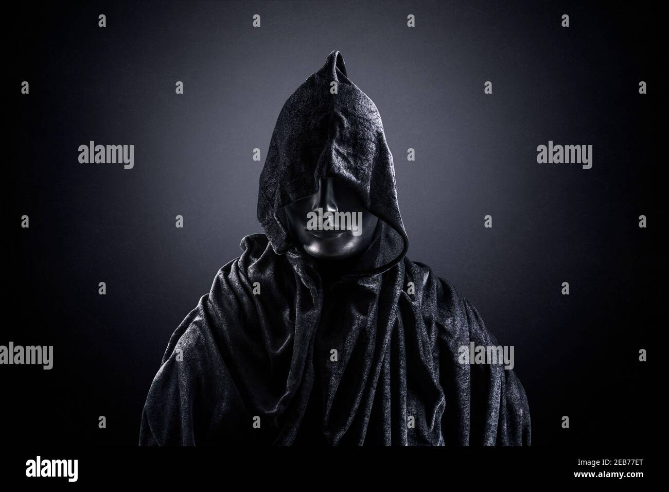 Scary figure with hooded cape in the dark Stock Photo - Alamy