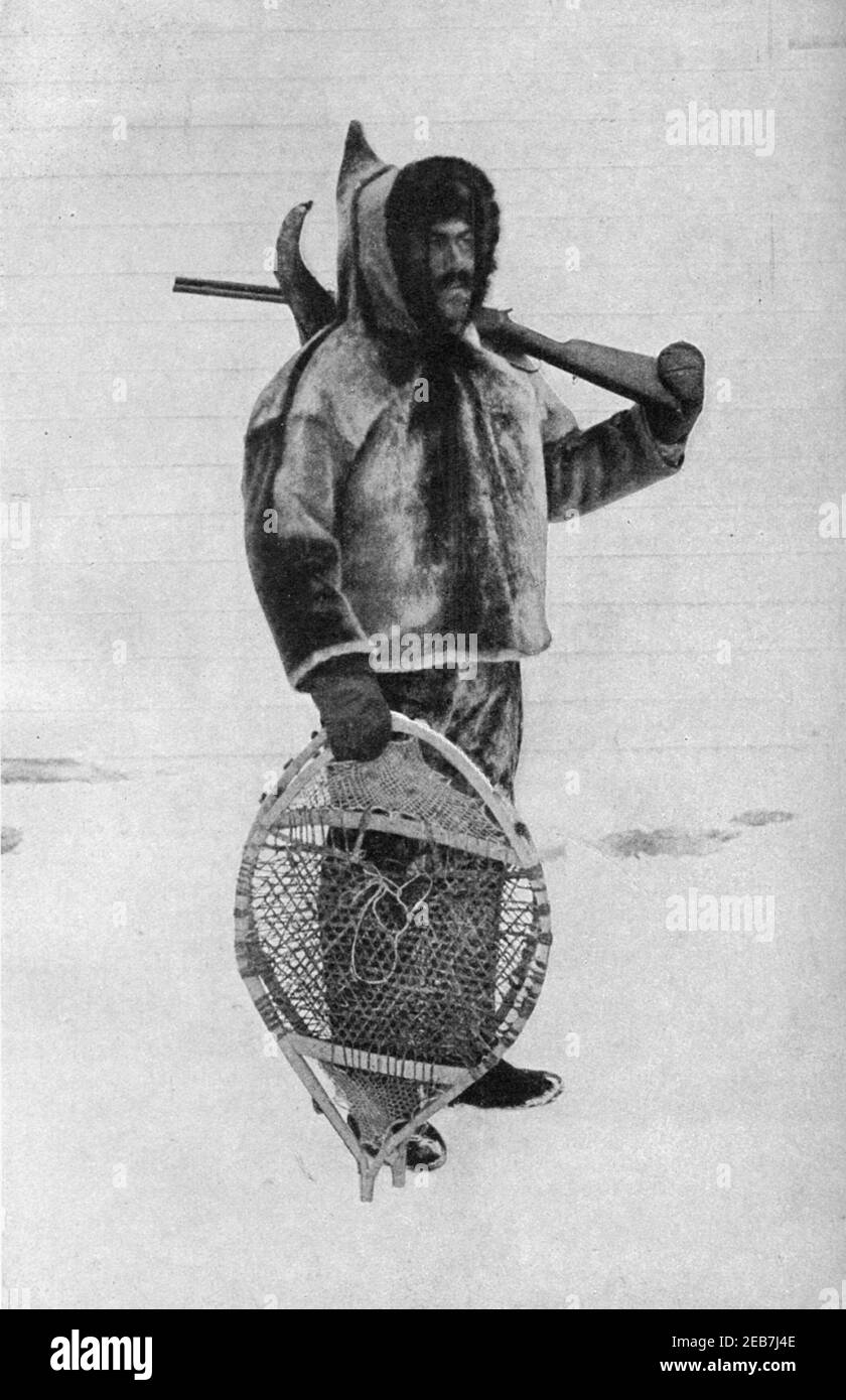 An early 20th century photo of a Labrador Inuit clad in a traditional seal skin parka with round Innu snowshoes and carrying a hunting rifle circa early 1900s Stock Photo