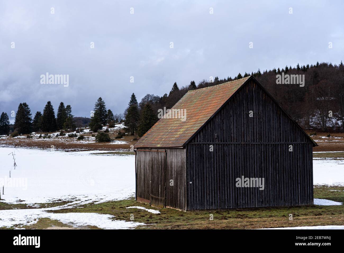 Wooden barn in a snow-covered field captured during the daytime Stock ...