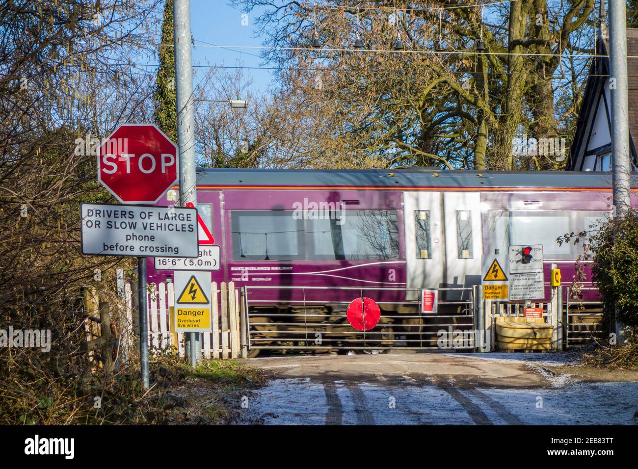 Train passing through a rural countryside railway level crossing with manually operated gate to open to allow you to cross  in  Oakhanger Cheshire Stock Photo