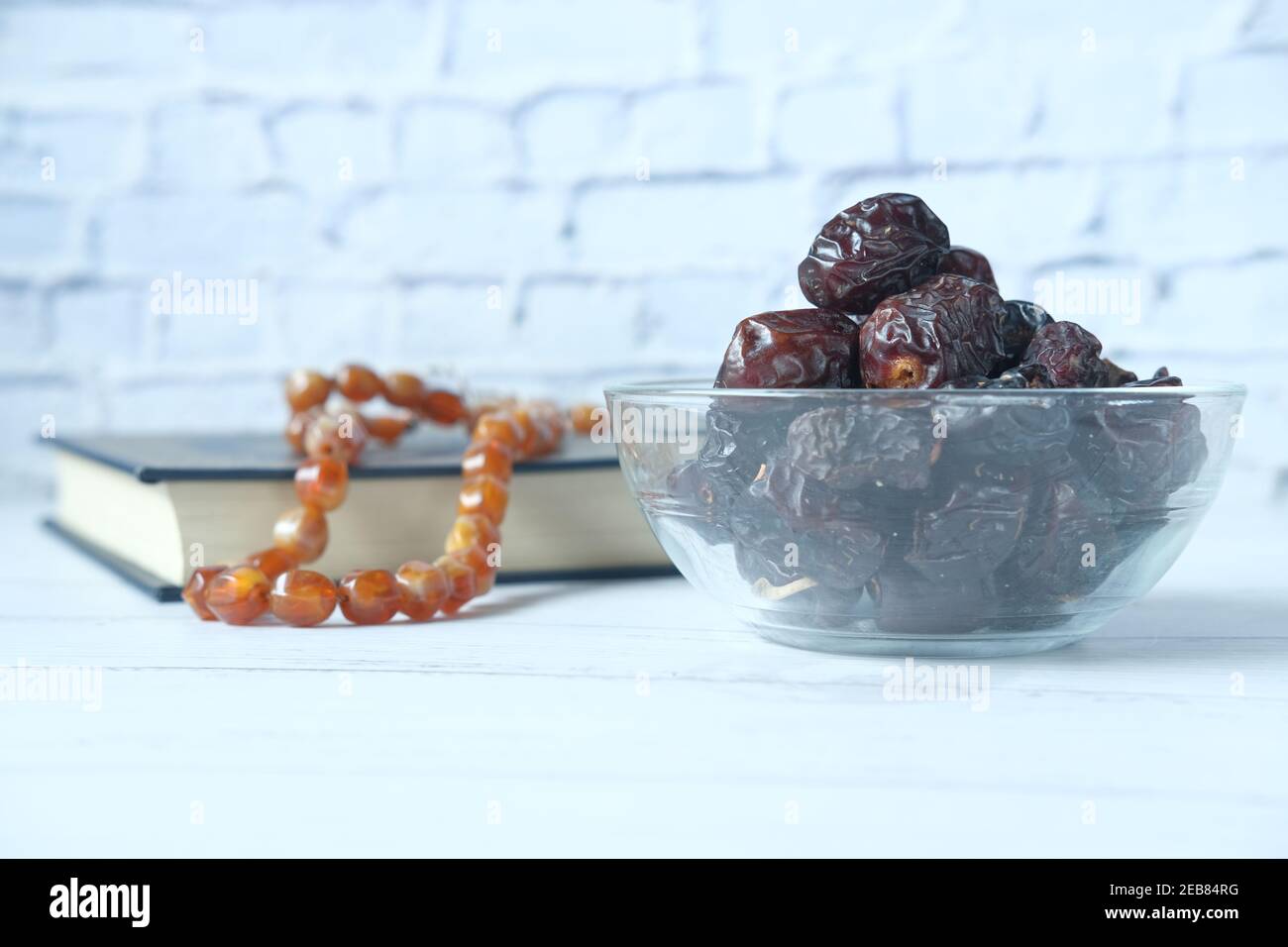 fresh date fruit in a bowl and holy book of quran on table  Stock Photo