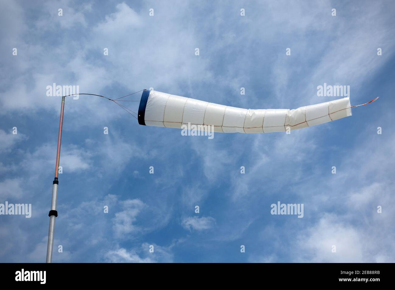 Bright windsock inflated horizontally by the wind, against the sky Stock Photo
